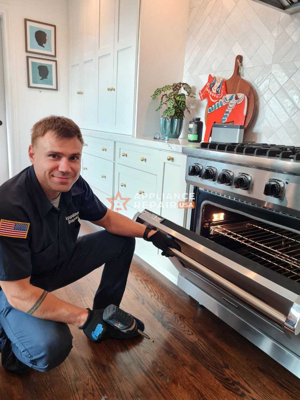 A technician kneels in front of an oven, inspecting it for repairs to ensure proper functionality