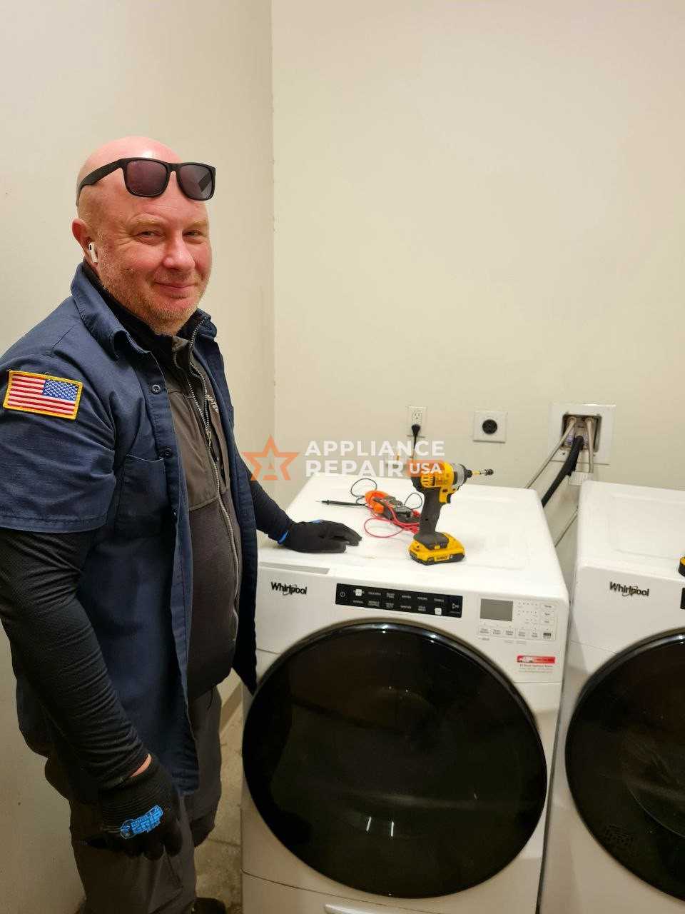 A man is positioned next to a washer and dryer, offering professional assistance